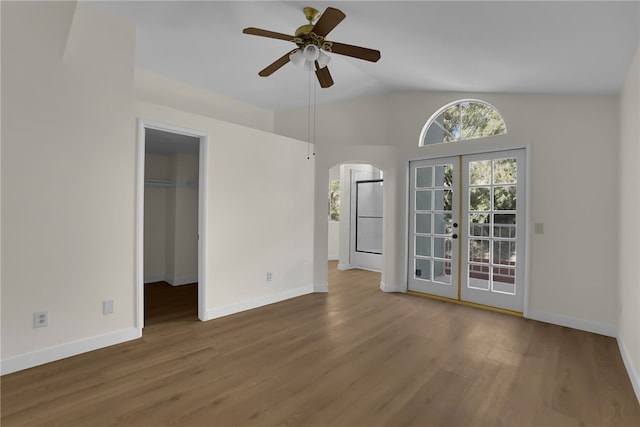 empty room with lofted ceiling, hardwood / wood-style flooring, french doors, and ceiling fan