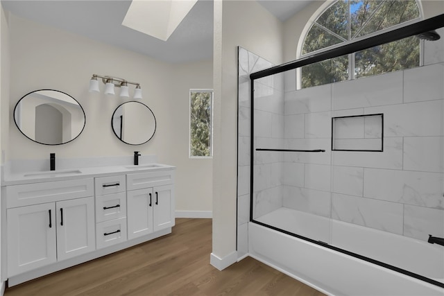 bathroom featuring hardwood / wood-style flooring, enclosed tub / shower combo, a skylight, and vanity