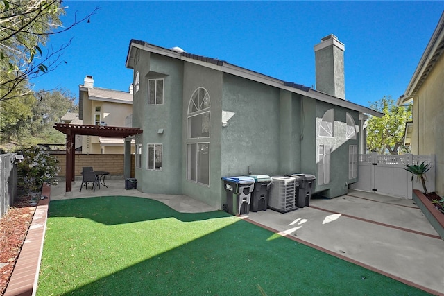 back of property with a lawn, a patio area, and a pergola