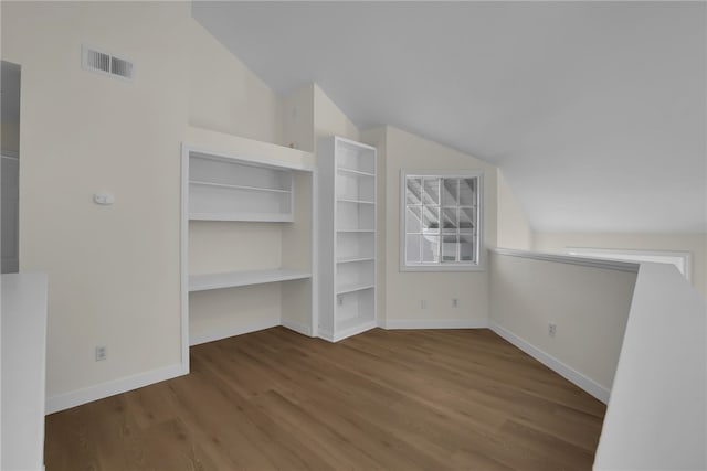 additional living space featuring built in shelves, vaulted ceiling, and hardwood / wood-style flooring