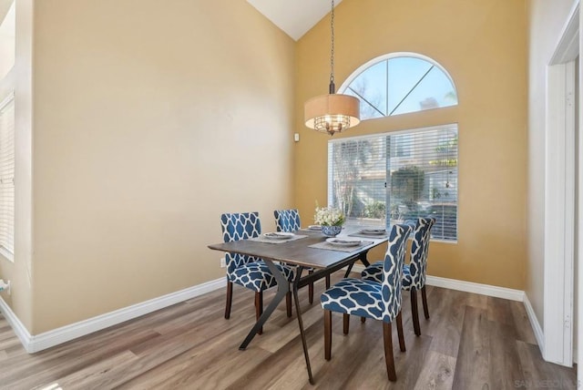 dining room featuring hardwood / wood-style flooring, an inviting chandelier, and high vaulted ceiling