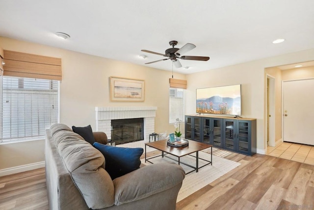 living room with light hardwood / wood-style floors, a fireplace, ceiling fan, and plenty of natural light