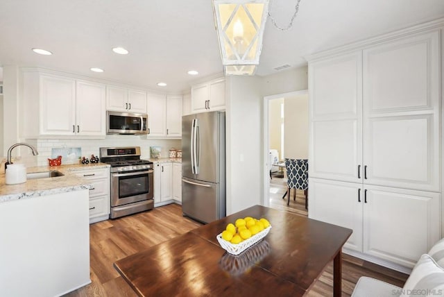 kitchen with stainless steel appliances, white cabinets, sink, and light wood-type flooring