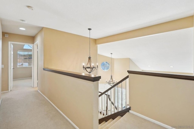 hallway with a notable chandelier, light carpet, and lofted ceiling