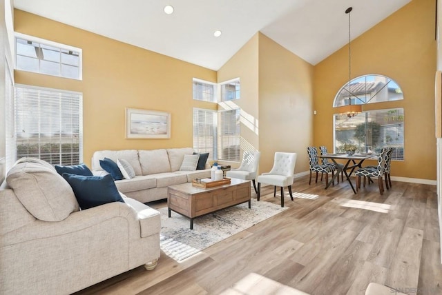 living room with high vaulted ceiling and light wood-type flooring