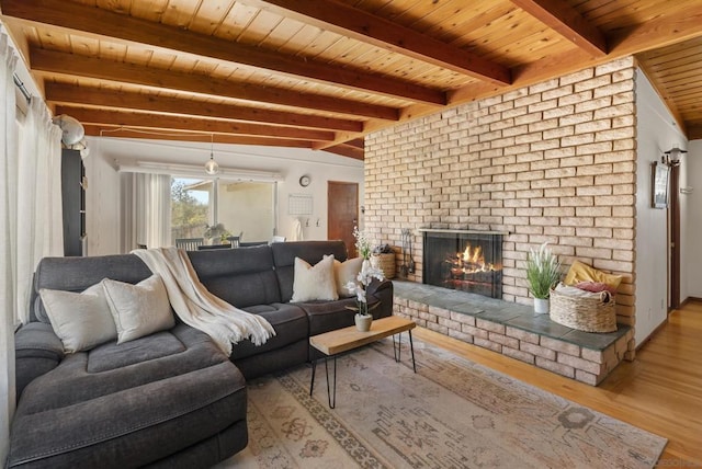 living room featuring a brick fireplace, light wood-type flooring, ceiling fan, wooden ceiling, and vaulted ceiling with beams