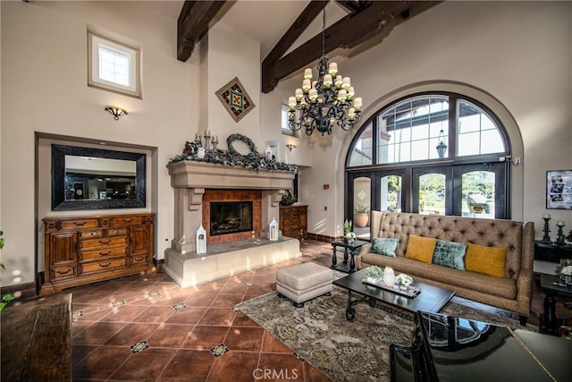 living room with a tile fireplace, beam ceiling, a high ceiling, a notable chandelier, and dark tile patterned flooring