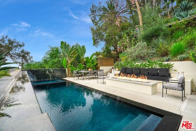 view of swimming pool with a patio area and a fire pit