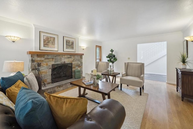 living room featuring light hardwood / wood-style floors, crown molding, and a stone fireplace