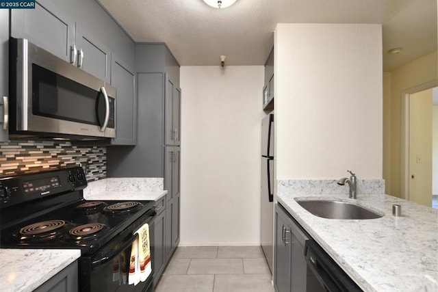 kitchen with light tile patterned floors, gray cabinets, tasteful backsplash, black appliances, and sink