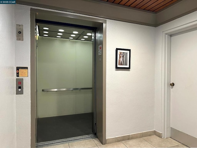 interior space with wooden ceiling, light tile patterned floors, and elevator