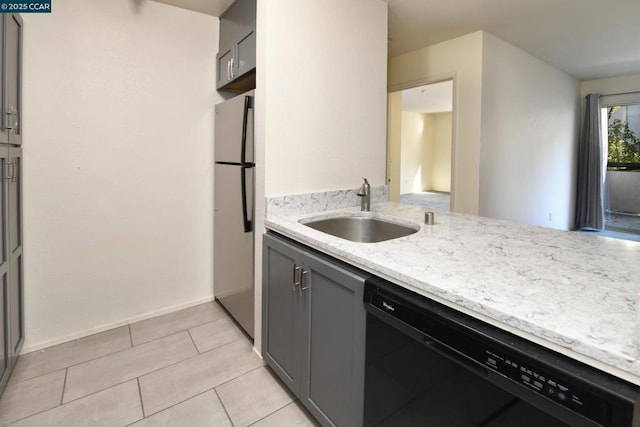 kitchen featuring light tile patterned floors, gray cabinets, black dishwasher, stainless steel refrigerator, and sink