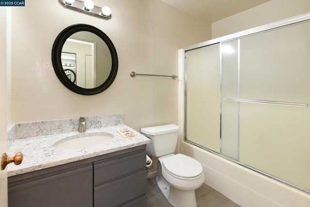 full bathroom featuring bath / shower combo with glass door, toilet, vanity, and tile patterned flooring