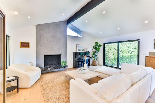 living room featuring light hardwood / wood-style floors, vaulted ceiling with beams, and a fireplace