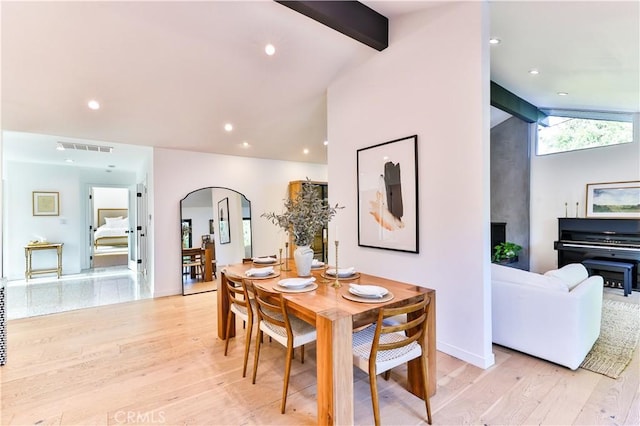 dining space with lofted ceiling with beams and light hardwood / wood-style flooring