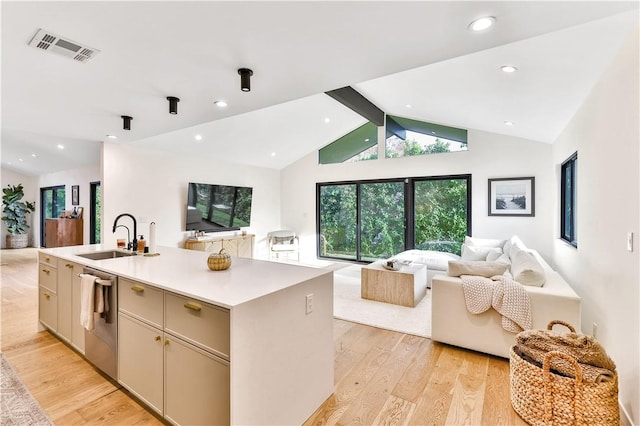 kitchen with dishwasher, an island with sink, lofted ceiling with beams, sink, and light hardwood / wood-style flooring