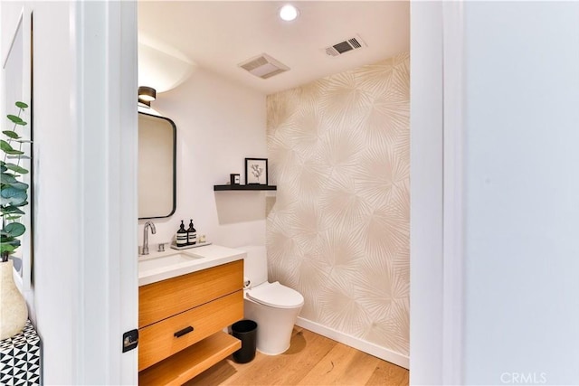 bathroom with toilet, vanity, and hardwood / wood-style flooring