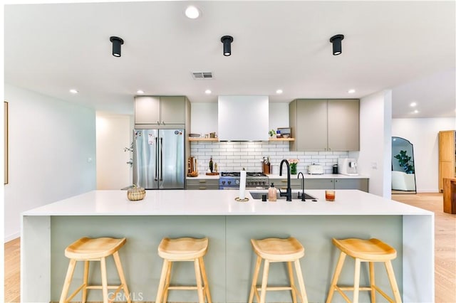 kitchen with backsplash, stainless steel appliances, a breakfast bar, and gray cabinetry