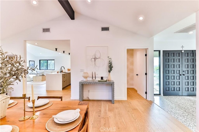 interior space featuring light hardwood / wood-style floors and vaulted ceiling with beams