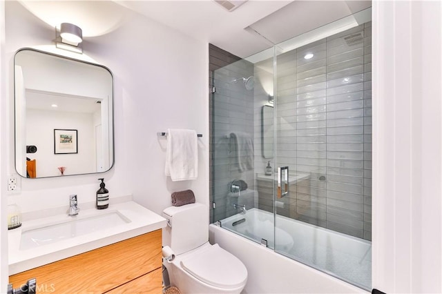 full bathroom with enclosed tub / shower combo, vanity, and toilet