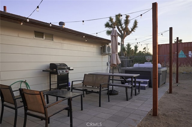 patio terrace at dusk with ac unit, a hot tub, and grilling area