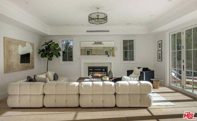 living room featuring ornamental molding, a tray ceiling, and light hardwood / wood-style flooring