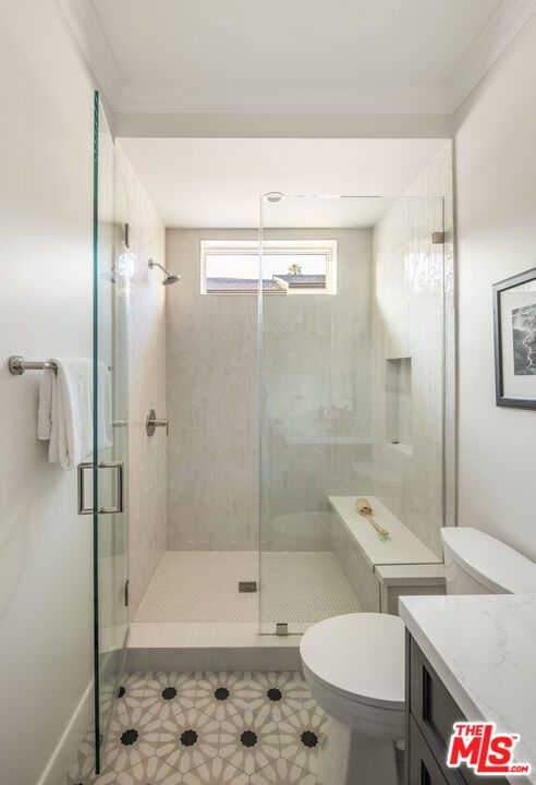 bathroom featuring ornamental molding, toilet, walk in shower, tile patterned floors, and vanity