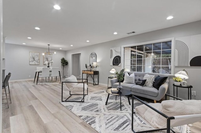 living room featuring light wood-type flooring and a chandelier