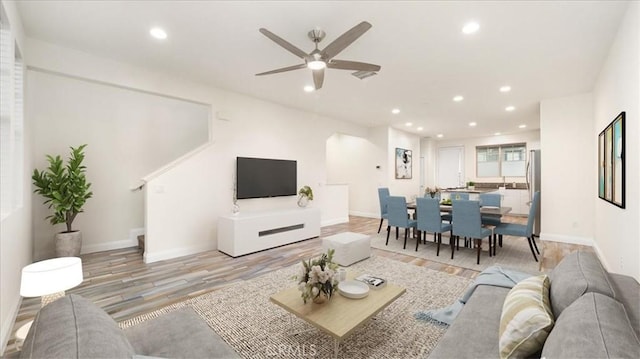 living room with ceiling fan and light hardwood / wood-style flooring