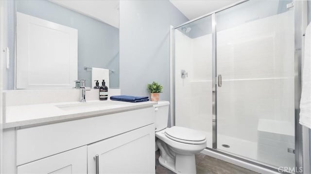 bathroom featuring toilet, hardwood / wood-style flooring, an enclosed shower, and vanity