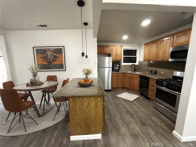 kitchen with sink, decorative light fixtures, backsplash, a kitchen island, and appliances with stainless steel finishes