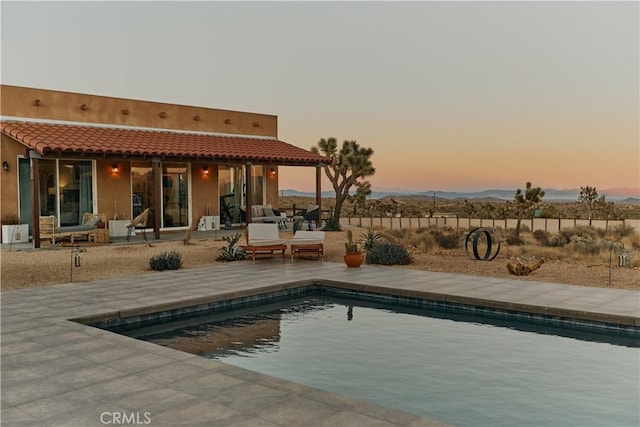 pool at dusk featuring a patio area