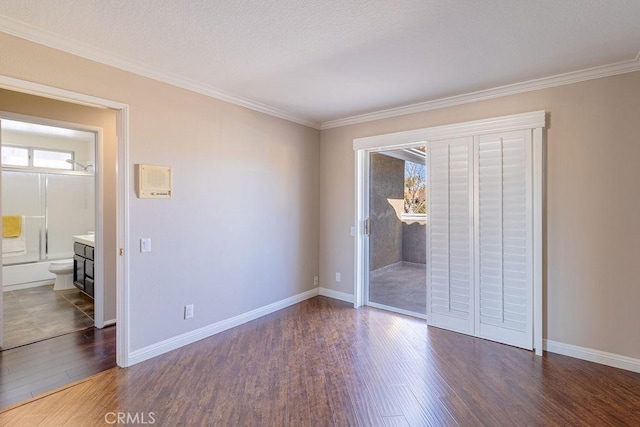 unfurnished bedroom with ensuite bath, a textured ceiling, crown molding, and dark hardwood / wood-style floors