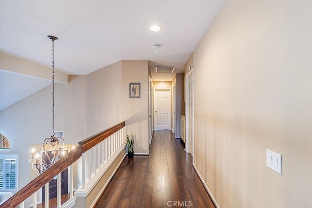 hallway with dark wood-type flooring and a notable chandelier