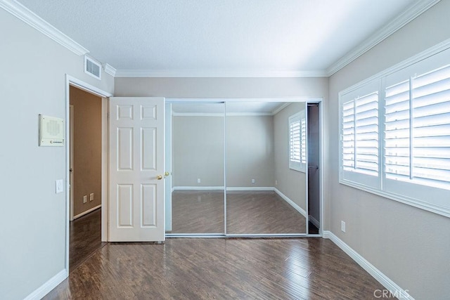 unfurnished bedroom featuring a closet, crown molding, and dark hardwood / wood-style floors