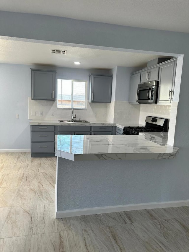 kitchen featuring stainless steel appliances, sink, gray cabinetry, and kitchen peninsula