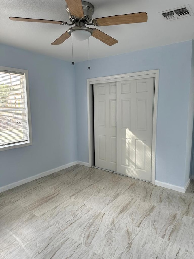 unfurnished bedroom with ceiling fan and a closet