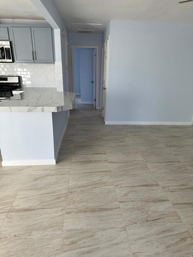 kitchen featuring appliances with stainless steel finishes, gray cabinetry, decorative backsplash, and light tile patterned floors