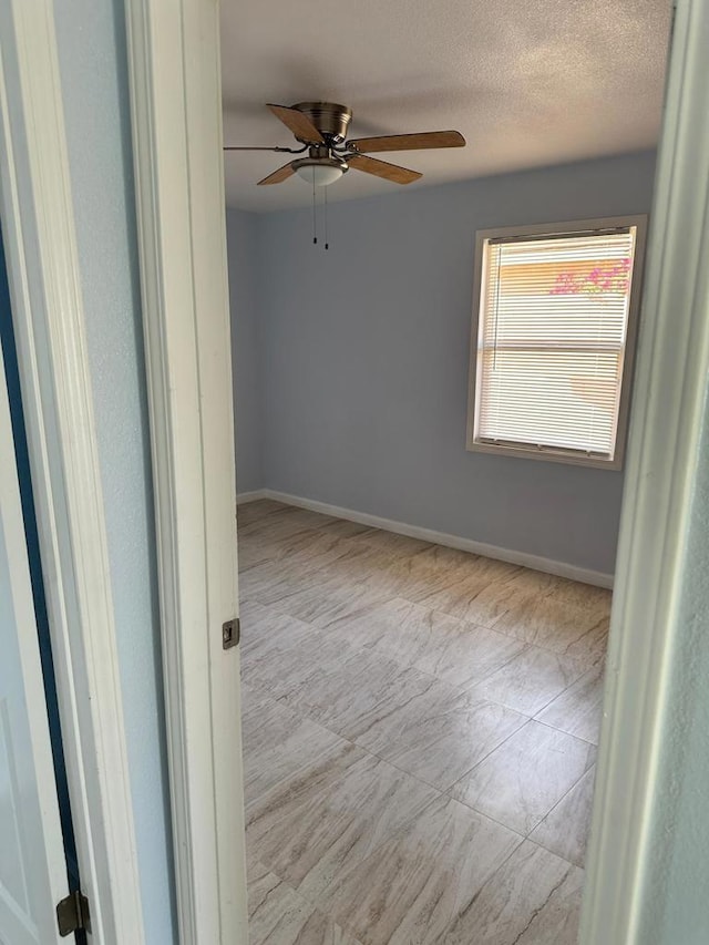 empty room with a textured ceiling and ceiling fan