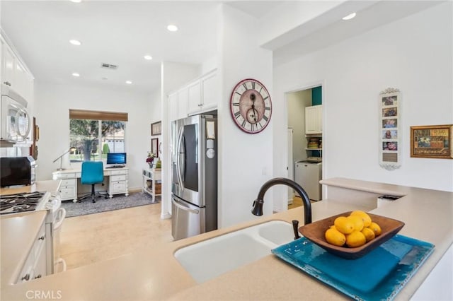 kitchen with white appliances, white cabinetry, washer / clothes dryer, and sink