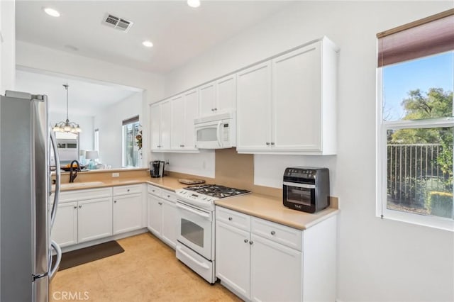 kitchen featuring white appliances, plenty of natural light, and white cabinets