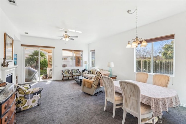 dining room featuring ceiling fan with notable chandelier and dark colored carpet