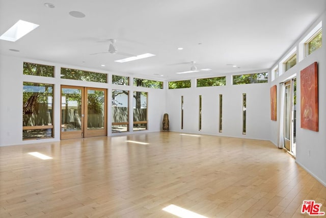 empty room with french doors, ceiling fan, light hardwood / wood-style floors, and plenty of natural light