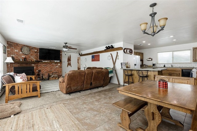 dining space featuring ceiling fan with notable chandelier and a brick fireplace