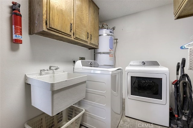 laundry area with sink, a textured ceiling, cabinets, washer and clothes dryer, and strapped water heater