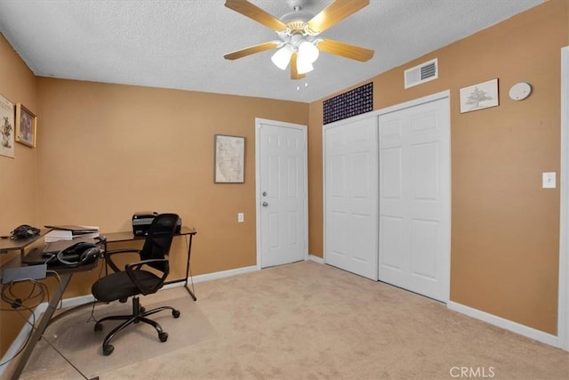 carpeted office space with a textured ceiling and ceiling fan