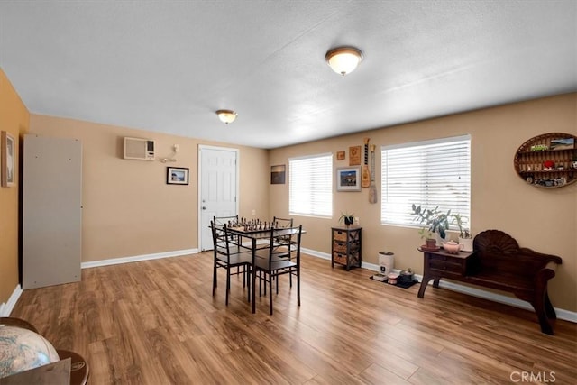 dining space featuring hardwood / wood-style flooring and an AC wall unit