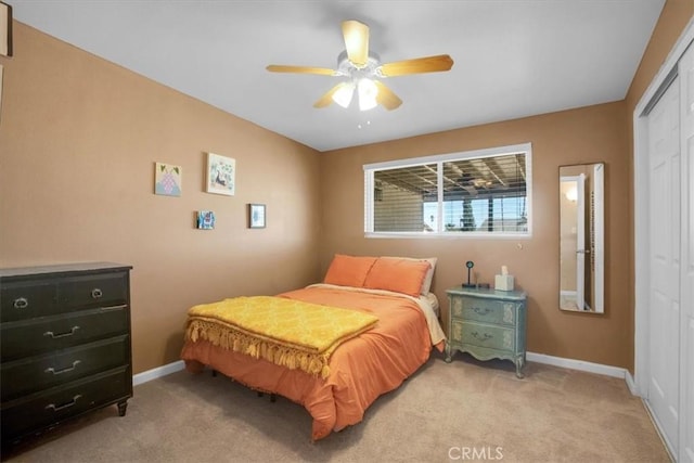 bedroom with ceiling fan, a closet, and light carpet