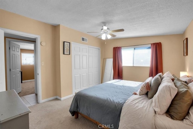 carpeted bedroom with a closet, ceiling fan, and a textured ceiling