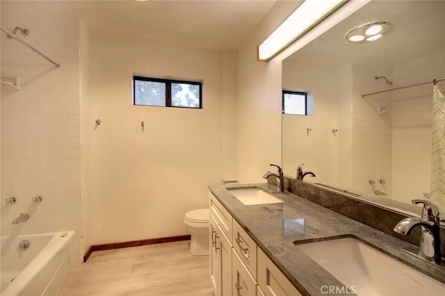 full bathroom featuring toilet, vanity, tiled shower / bath combo, and a healthy amount of sunlight